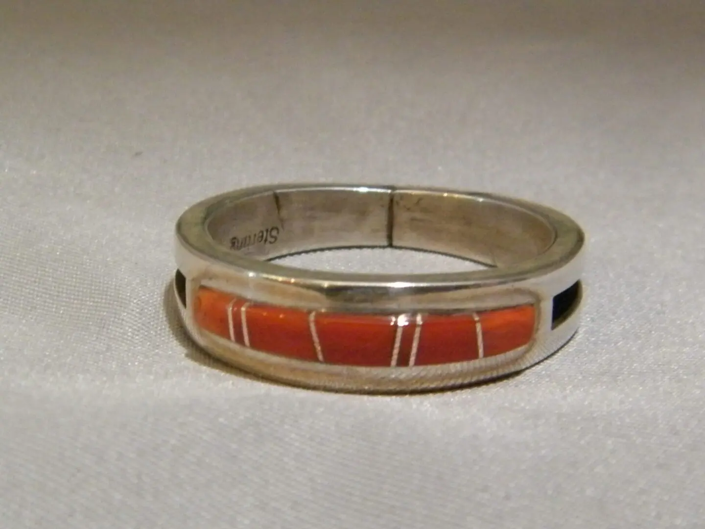 A Silver Ring With Orange Stone and Gold Lines