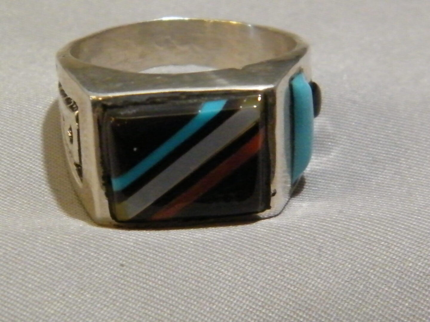 A Silver Ring With Black, Red and Blue Color Square Stone